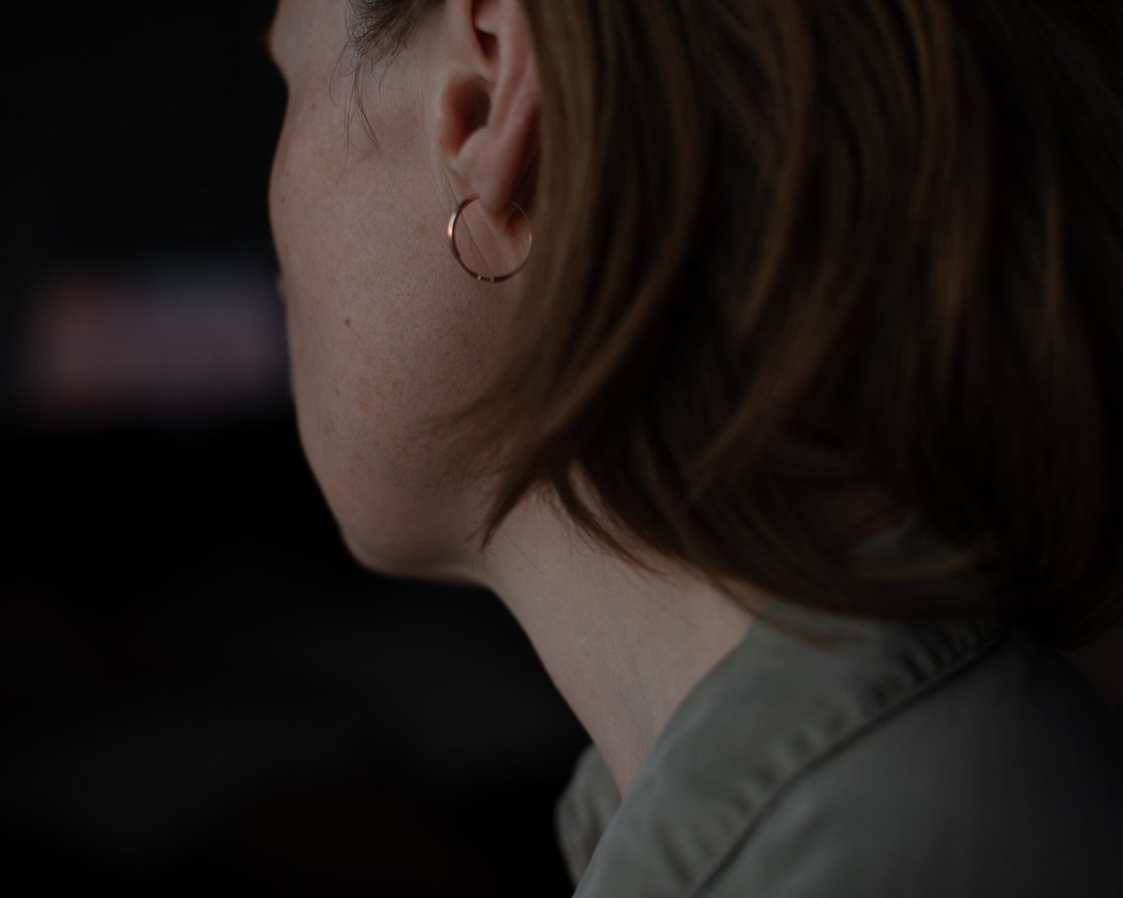 Cinematic self portrait detail by Anya Baro featuring ear, neck and gold hoop earring in soft evening light.